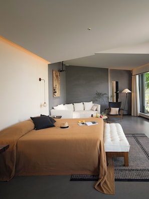 A modern bedroom with a large bed, a sofa, a bench, and a chair. There is a window providing a view of the outdoors. - XiyeSeclusionResortHotel (Xishuangbanna Dai)