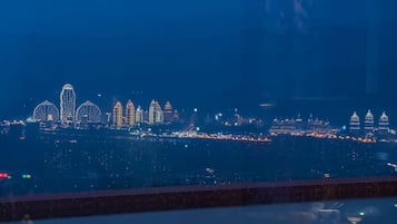 Ein Esstisch mit Geschirr und Gläsern, mit Blick auf eine beleuchtete Stadtlandschaft bei Nacht.