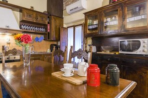 Een keuken met houten kastjes, een magnetron en een koffiezetapparaat op het aanrecht.
