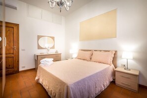 Ein Schlafzimmer mit einem Bett, Nachttischen, einem Spiegel und einer Chandelieber.