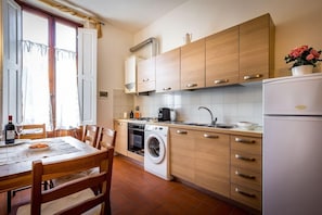 Eine kleine Küche mit Holzausstattung, einer Waschmaschine und einem Kühlschrank.