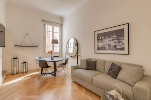 Una sala de estar moderna con un sofá, una mesa de comedor con sillas y un cuadro grande en la pared.