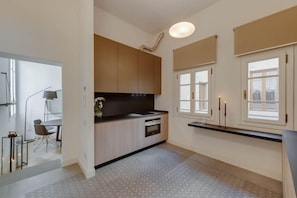 Una cocina moderna con horno empotrado, zona de comedor con mesa y sillas, y ventana con vistas.