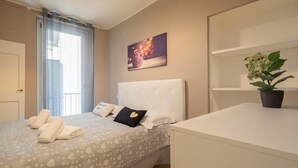 Ein Hotelzimmer mit einem Bett, einem Nachttisch, einer Topfpflanze und einem Bild an der Wand.