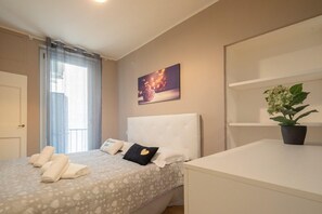 Una habitación de hotel con una cama, una mesita de noche, una planta en maceta y un cuadro en la pared.