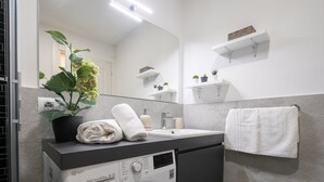 Ein modernes Badezimmer mit Waschbecken, Spiegel, Topfpflanze und Handtuchhalter.