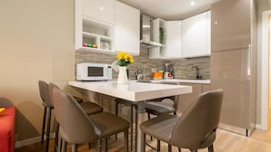Eine moderne Küche mit weißen Schränken, einer zentralen Kochinsel mit Stühlen, einer Mikrowelle und einem Kühlschrank.