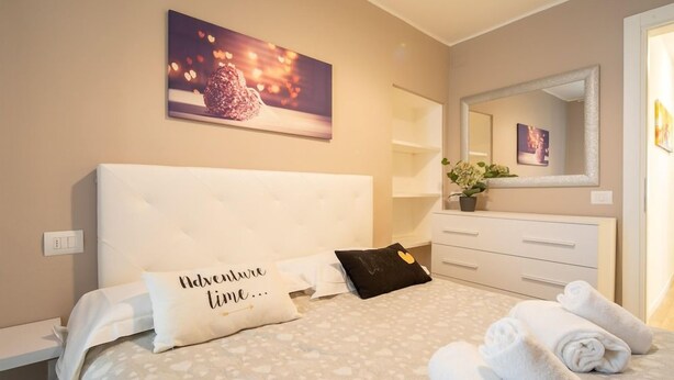 Ein Hotelzimmer mit einem Bett, einem Nachttisch, einer Kommode, einem Spiegel und einem Wandbild.