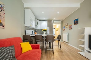 Una sala de estar moderna con un sofá rojo, un comedor con sillas y una cocina al fondo.