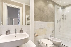 Un baño moderno con un lavamanos grande, inodoro, bidé y ducha a ras de suelo.
