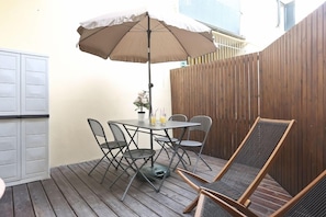 Un patio con una mesa, sillas, cerca de madera y un armario blanco.