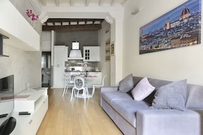 Una sala de estar moderna con un sofá gris, un televisor de pantalla plana y un cuadro de un paisaje urbano.
