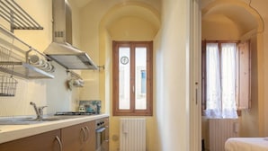 Eine kleine Küche mit Herd, Spüle und einem Fenster mit Vorhängen.