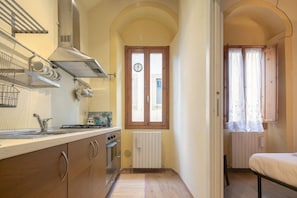 Una cocina pequeña con estufa, lavamanos y una ventana con cortinas.