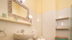 Ein Badezimmer mit Waschbecken, Spiegel, Toilette und Regalen.