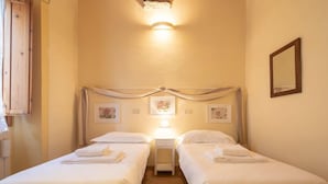 Ein Hotelzimmer mit zwei Betten, einem Nachttisch mit Lampe und einem Spiegel an der Wand.