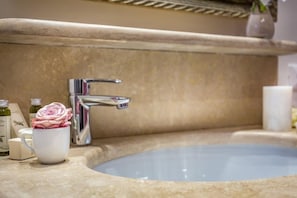 Un baño con lavamanos, espejo y artículos de tocador.