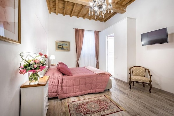 Un dormitorio con cama, una silla, un televisor y una araña.