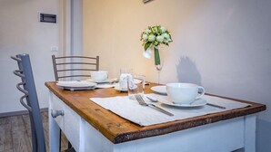 A dining table set with white dishes, a glass of water, and a floral arrangement. - Arno Apartment B (Florence)