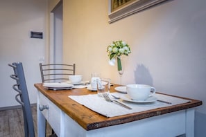 Mesa de comedor dispuesta con vajilla blanca, un vaso de agua y un arreglo floral.