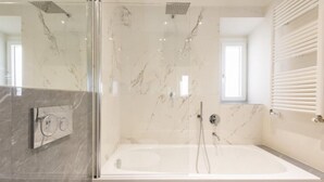 Ein modernes Badezimmer mit einer Glasdusche, einer freistehenden Badewanne und einer Wand mit Marmorfliesen.