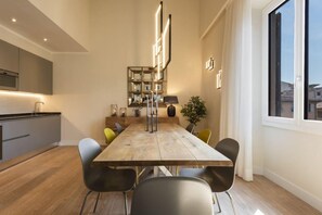 Un comedor moderno con una mesa de madera, sillas negras y una cocina al fondo.