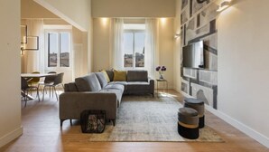 Ein modernes Wohnzimmer mit einer Eckcouch, einem Essbereich mit Stühlen und einem großen Fenster mit Blick auf die Stadt.