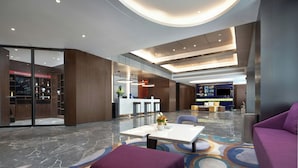 Un lobby moderno de hotel con mostrador de recepción, zona de estar y una pantalla grande.