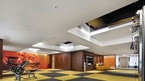 Un gimnasio con equipamiento de ejercicio, piso a cuadros amarillo y negro, y un espejo grande.