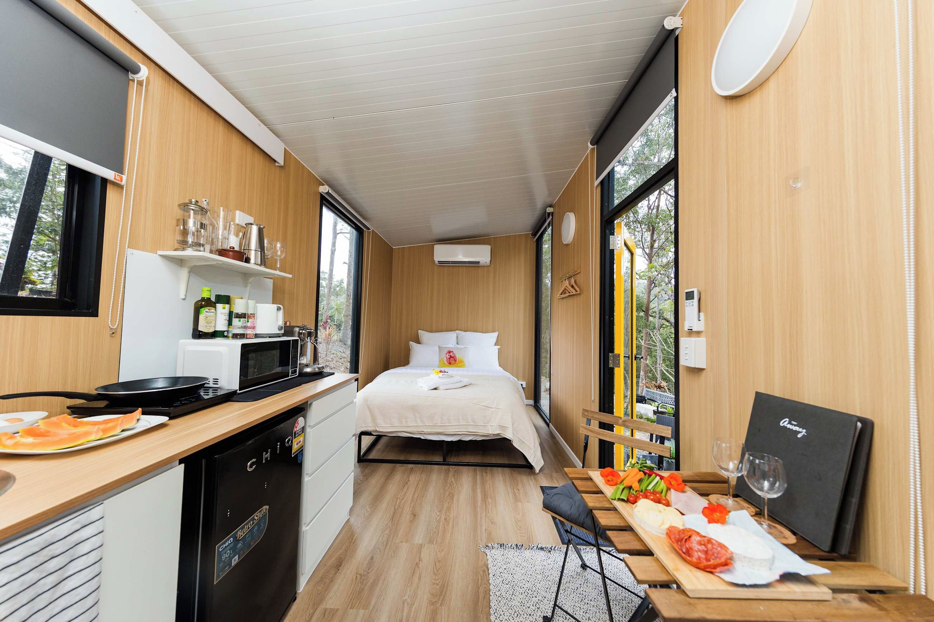 A compact room with a bed, kitchenette, and a dining area with a table set for a meal.