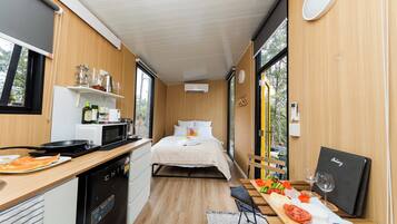 A compact room with a bed, kitchenette, and a dining area with a table set for a meal.