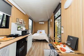 A compact room with a bed, kitchenette, and a dining area with a table set for a meal.
