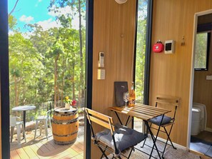 A room with a wooden table, two chairs, a small barrel, a bottle, and a glass. - GC Hinterland Hideaway by Tiny Away (Bonogin)