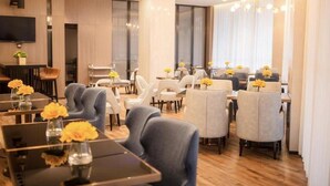 A modern hotel dining area with multiple tables and chairs, a flat-screen TV mounted on the wall, and a chandelier. - Echarm Hotel Xiantao Stadium (Beijing)