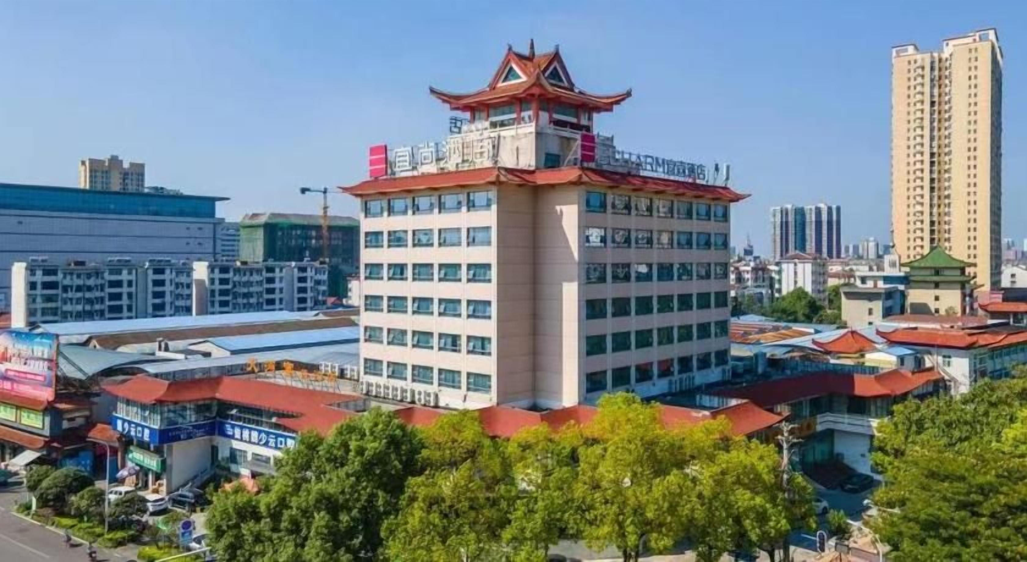A multi-story hotel with a traditional architectural style, featuring a prominent tower with a red roof and a pagoda-like structure on top.