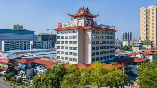 A multi-story hotel with a traditional architectural style, featuring a prominent tower with a red roof and a pagoda-like structure on top. - Echarm Hotel Xiantao Stadium (Beijing)