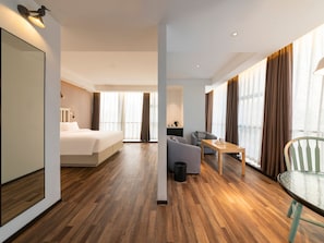A hotel room with a bed, a sofa, a dining table, and a chair. - Borrman Hotel (Jinan)