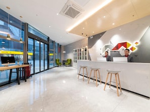 A modern reception area with a desk, chairs, and a large window. - Borrman Hotel (Jinan)