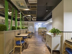 A modern interior with wooden flooring, green pillars, and a central dining area with tables and chairs. - Borrman Hotel (Jinan)