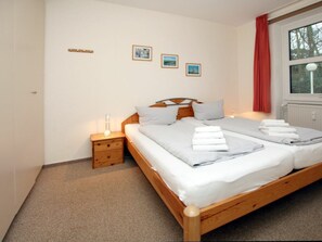 A double bed with two pillows and a bedside table with a lamp. - 21 - Waldstrasse 19a (Wyk auf Foehr)