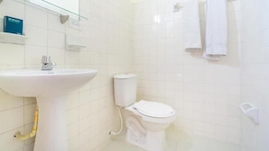 A bathroom with a white sink, toilet, and a glass shelf with toiletries. - Ayenda Astoria Real (Cali)