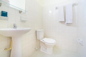 A bathroom with a white sink, toilet, and a glass shelf with toiletries. - Ayenda Astoria Real (Cali)