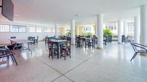 A spacious indoor area with multiple tables and chairs arranged for dining or meetings. - Ayenda Astoria Real (Cali)