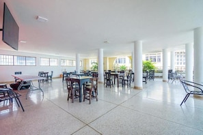 A spacious indoor area with multiple tables and chairs arranged for dining or meetings. - Ayenda Astoria Real (Cali)