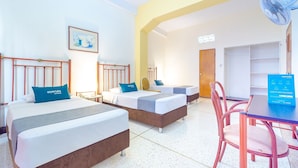 A hotel room with two beds, a desk, a chair, a fan, and a door. - Ayenda Astoria Real (Cali)