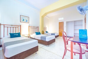 A hotel room with two beds, a desk, a chair, a fan, and a door. - Ayenda Astoria Real (Cali)