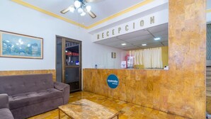 A reception area with a sofa, a coffee table, and a reception desk. - Ayenda Astoria Real (Cali)