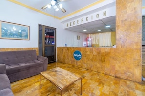 A reception area with a sofa, a coffee table, and a reception desk. - Ayenda Astoria Real (Cali)
