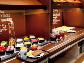Un buffet proposant une variété de plats, notamment des fruits, des légumes et des boissons.