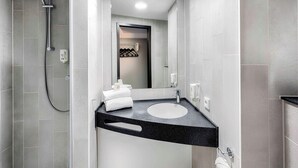 A modern bathroom with a shower, a sink, and a mirror. - Ibis Budget Flensburg City (Flensburg)